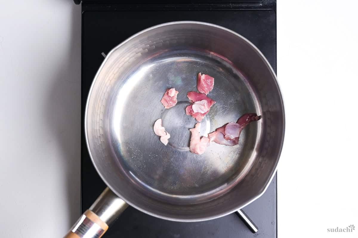 duck breast scraps frying in a saucepan on the stove top