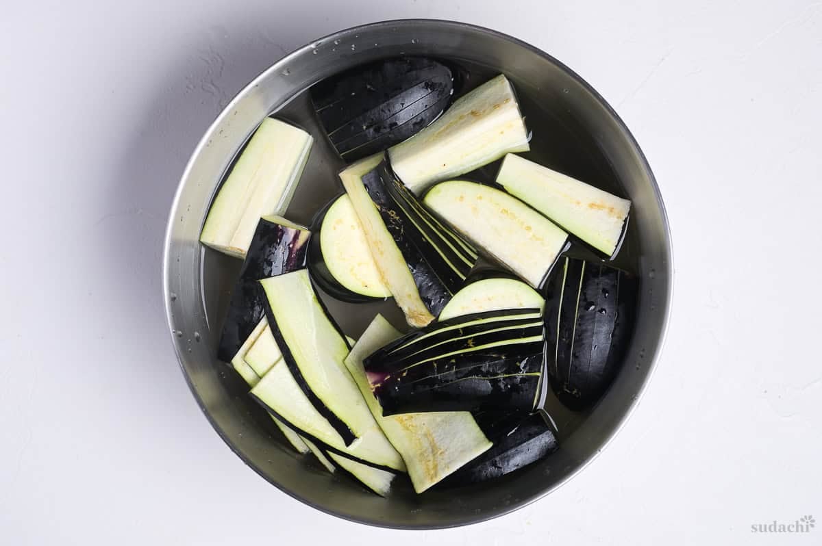 Cut eggplant for tempura soaking in a bowl of water