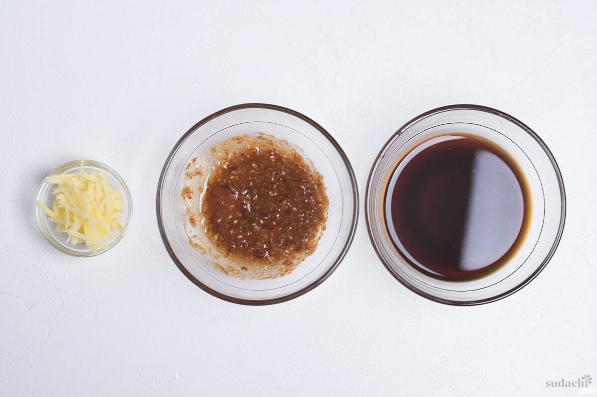 Ingredients prepared for making sanshoku soboro donburi (rice bowl). Julienned ginger, sauce for spinach and sauce for chicken soboro in separate glass bowls.