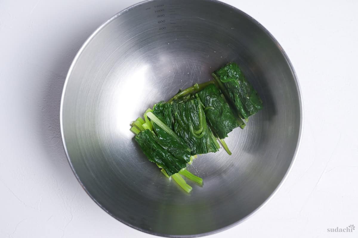 Blanched Oriental spinach squeezed and placed in a mixing bowl.