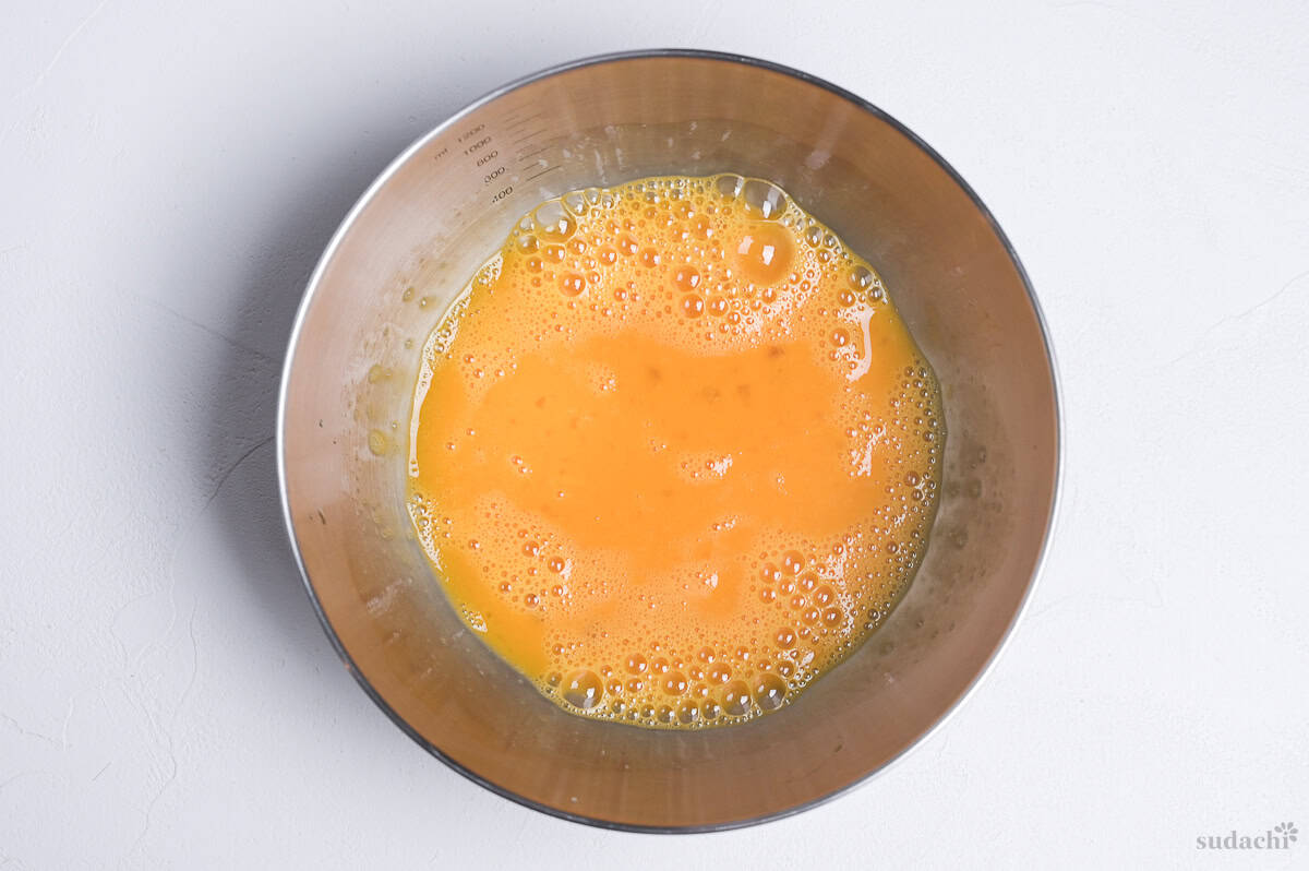 whisked egg in steel mixing bowl.