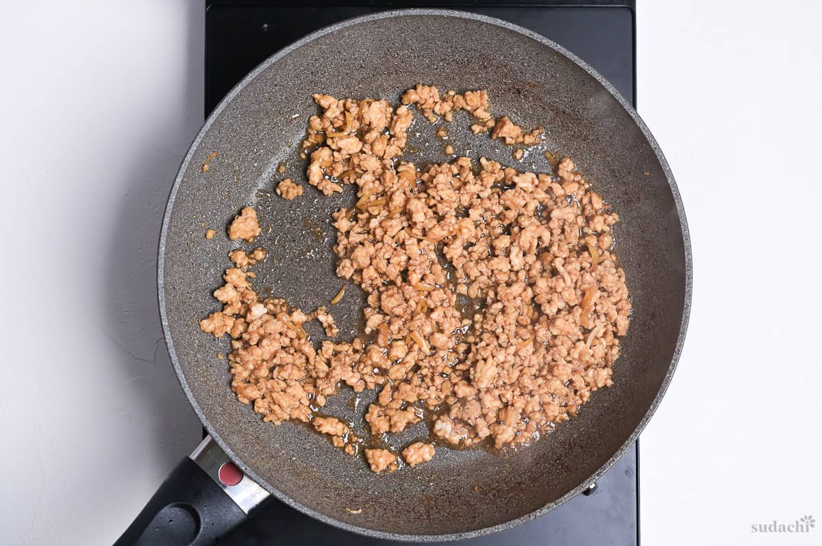 Ground chicken with sauce in a frying pan to make soboro for sanshoku donburi