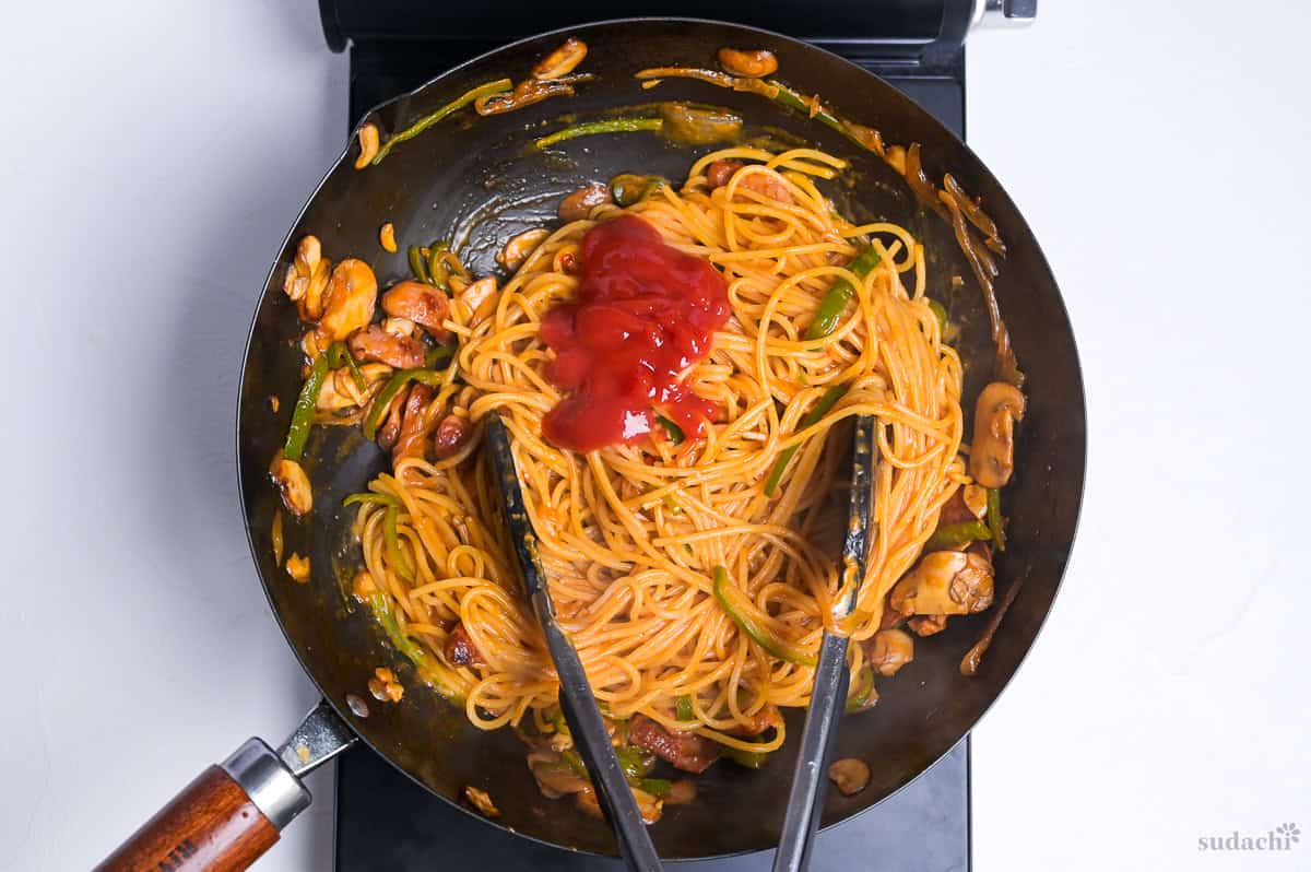 Spaghetti napolitan with extra ketchup in a wok on the stove top