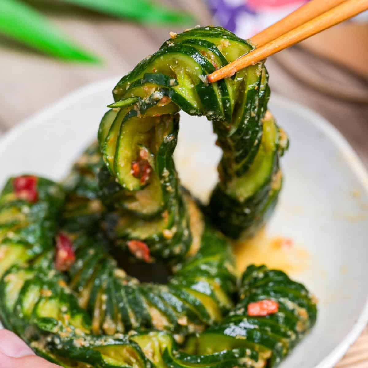 Spicy miso accordion cucumber lifted with light wooden chopsticks