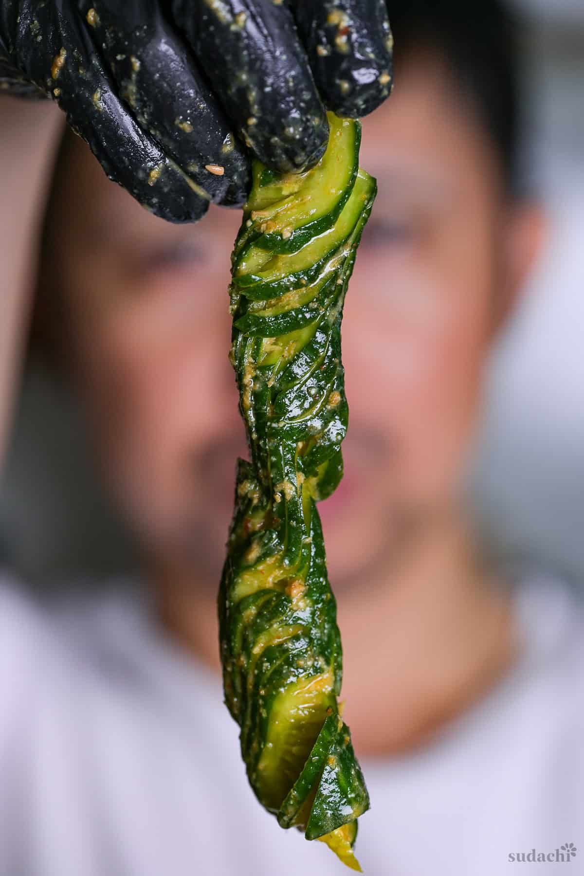 Yuto Omura holding up one spicy miso accordion cucumber