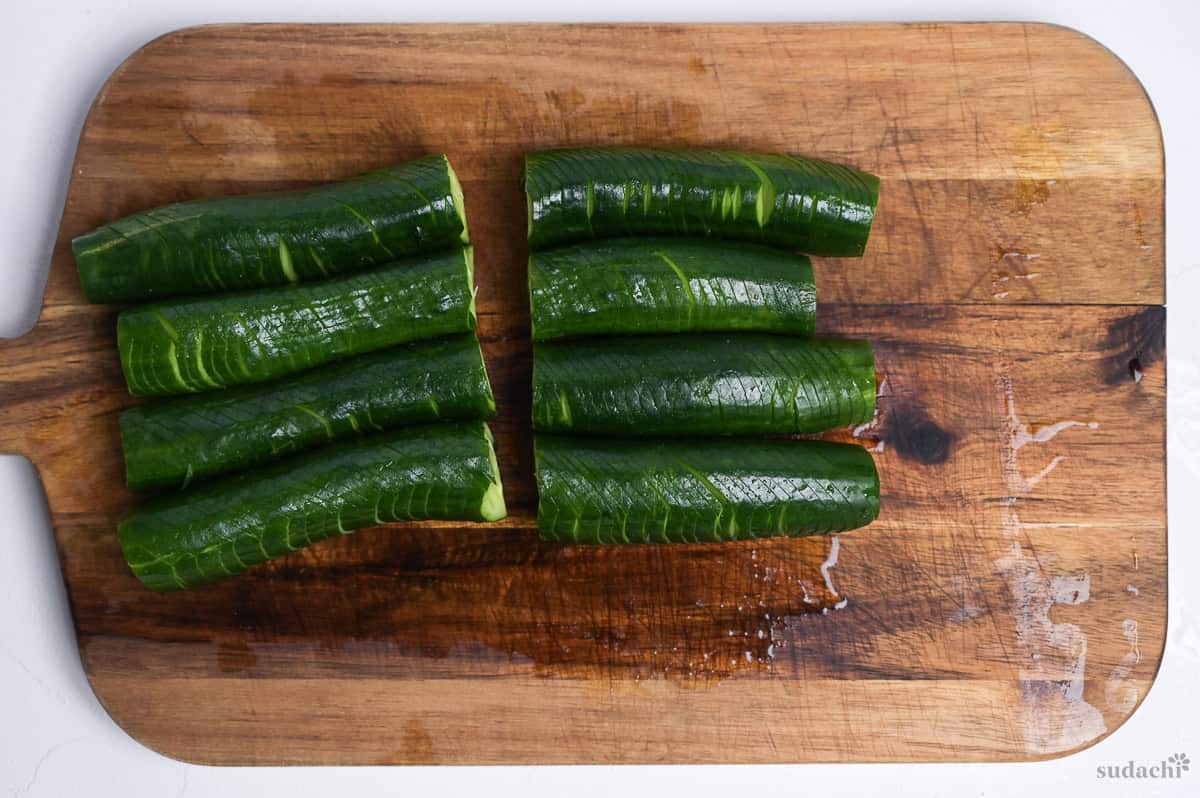 accordion cut Japanese cucumbers cut in half on a wooden cutting board