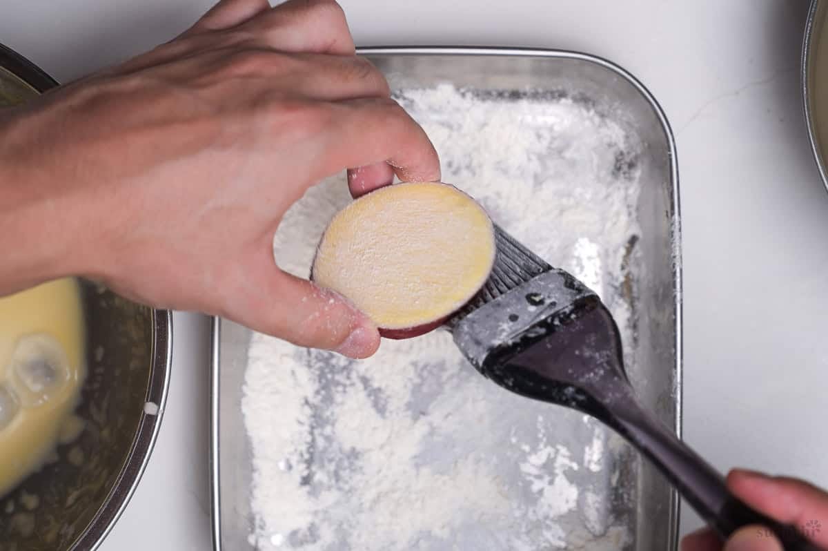 brushing a thick slice of Japanese sweet potato with cornstarch