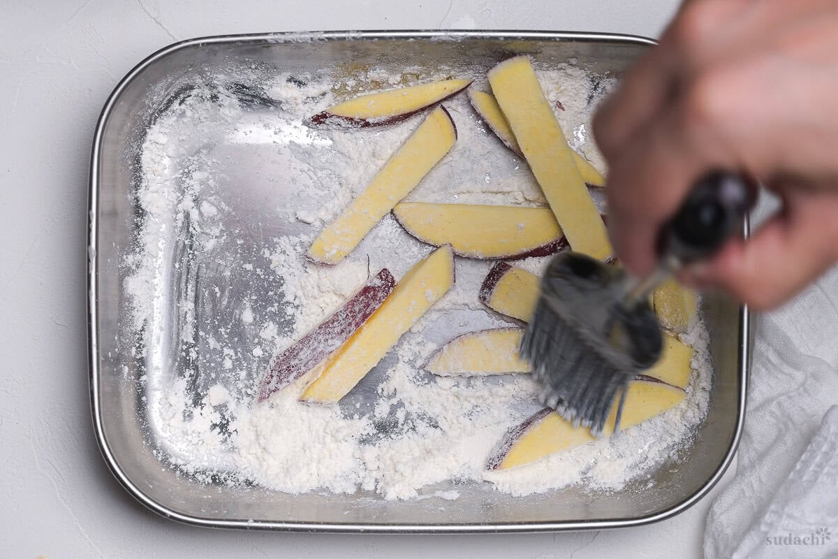 brushing a sticks of Japanese sweet potato with cornstarch