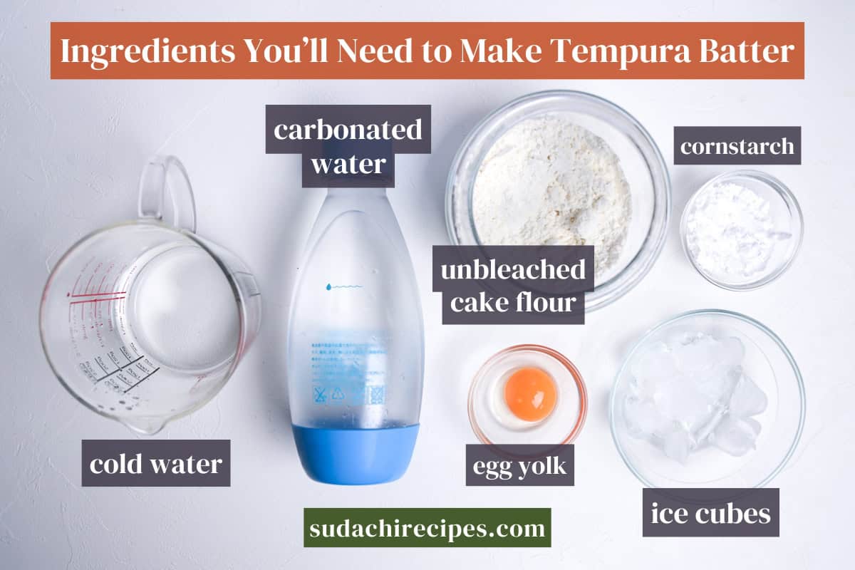 Ingredients needed to make tempura batter on a white background with labels. From top to bottom, left to right: carbonated water, cornstarch, unbleached cake flour, cold water, egg yolk, ice cubes.