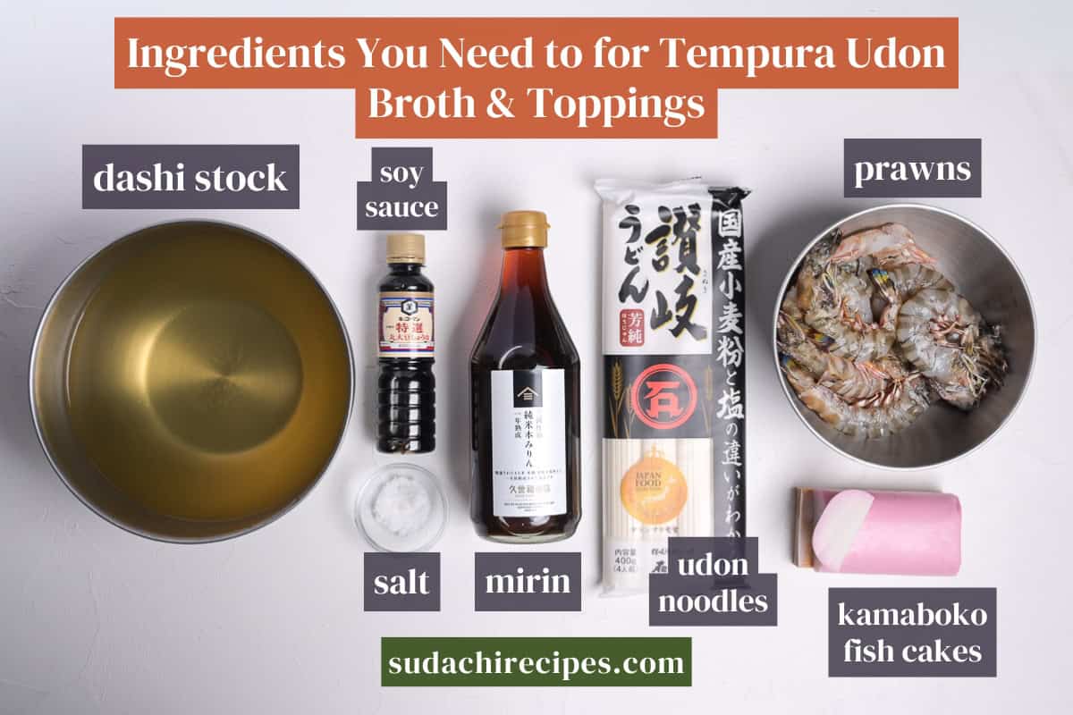 Ingredients needed to make tempura udon broth and toppings on a white background with labels. From top to bottom, left to right: dashi stock, soy sauce, prawns, salt, mirin, udon noodles, kamaboko fish cakes.