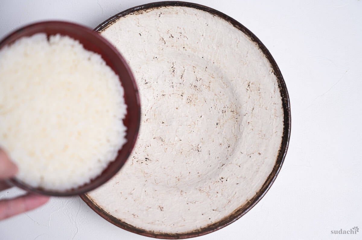 rice packed into a bowl to make a dome with an empty plate below it