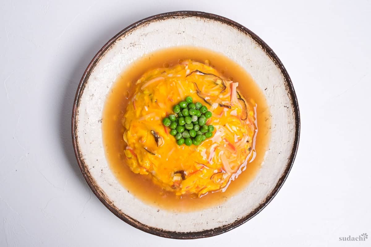 tenshinhan made with plain rice, crab omelette and a glossy homemade sauce and topped with green peas.
