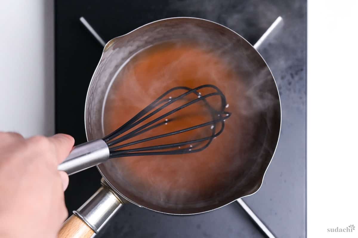 whisking tenshinhan sauce in a saucepan on the stove top