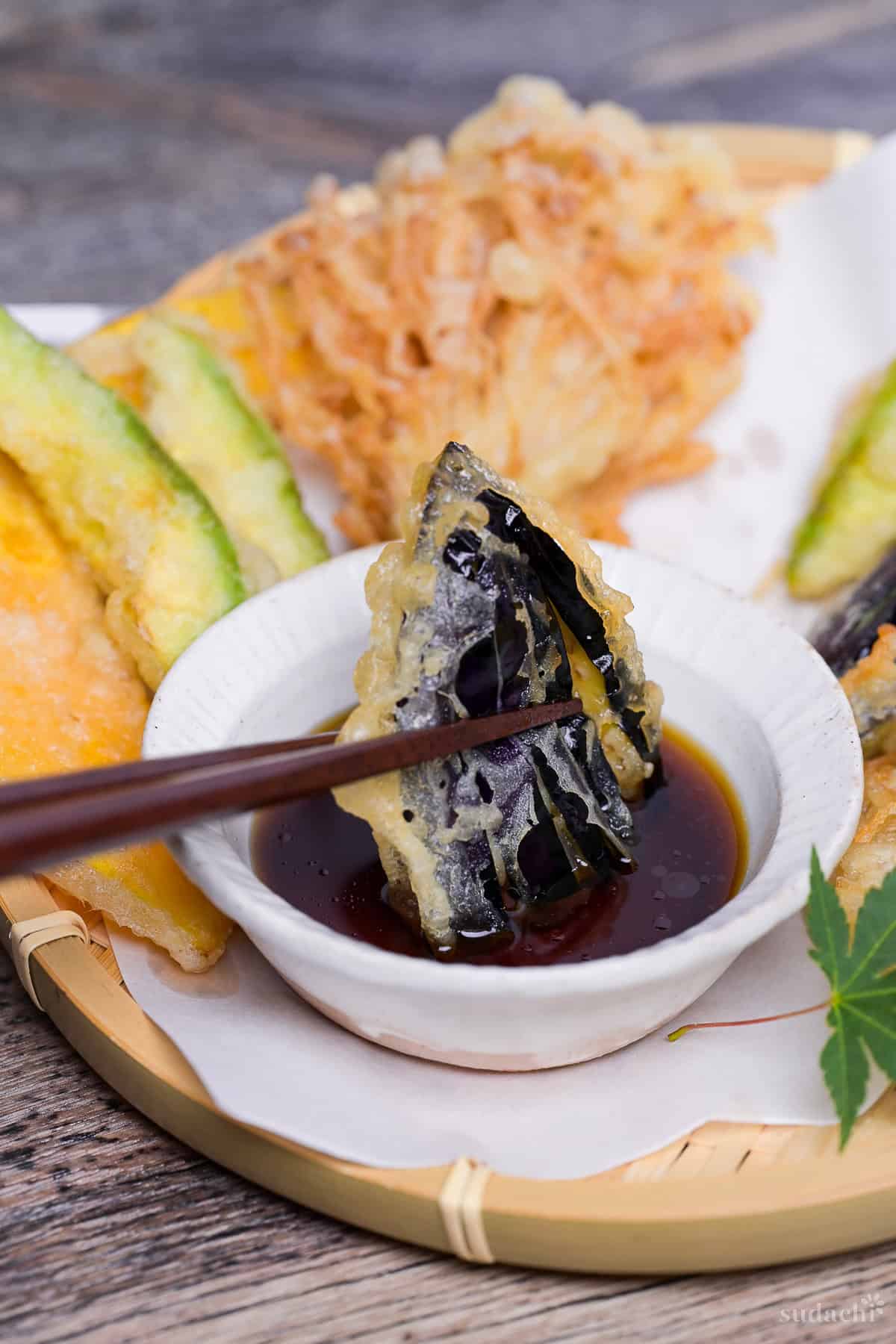 dipping a piece of eggplant tempura in homemade tentsuyu tempura dipping sauce