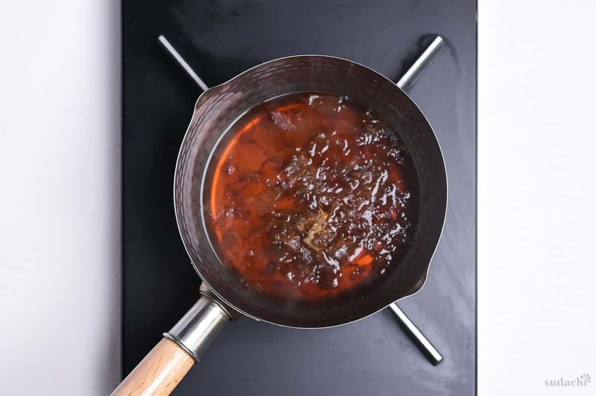 steeping bonito flakes in hot homemade tentsuyu sauce in a sauce pan on the stove top