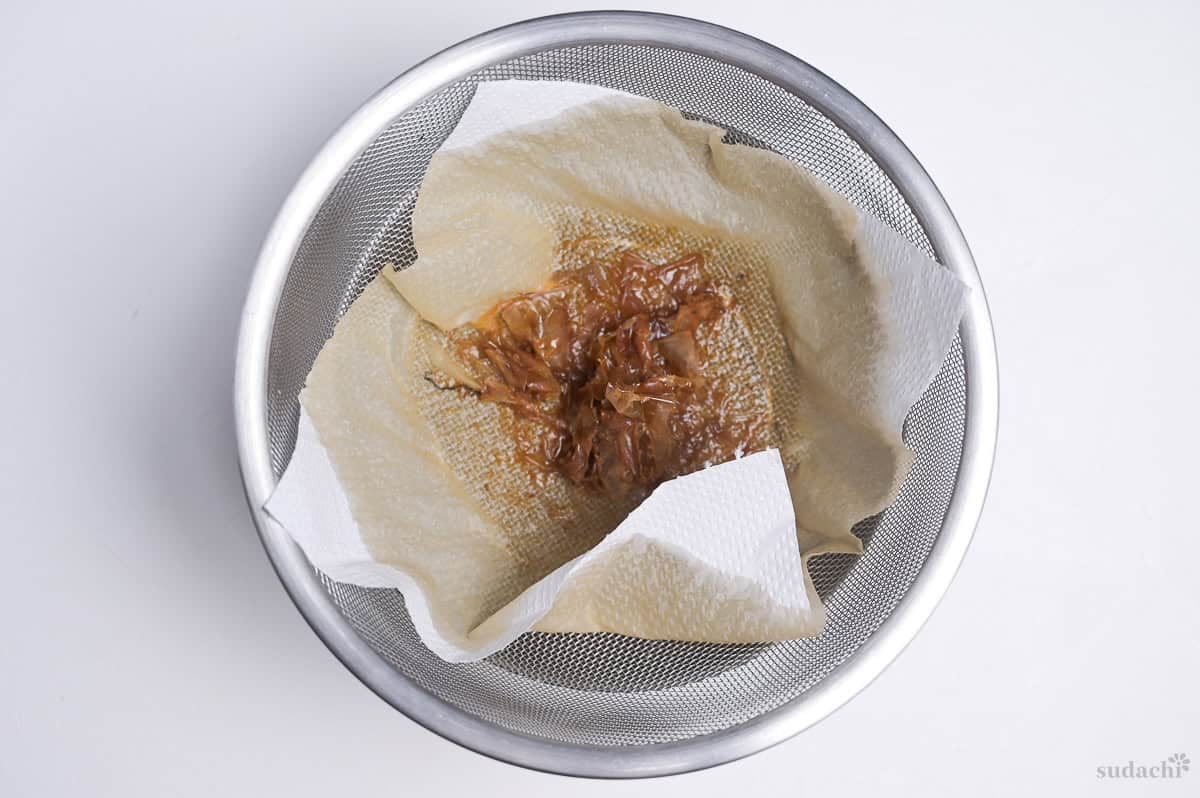 bonito flakes in a kitchen paper lined fine mesh sieve after straining homemade tentsuyu tempura dipping sauce