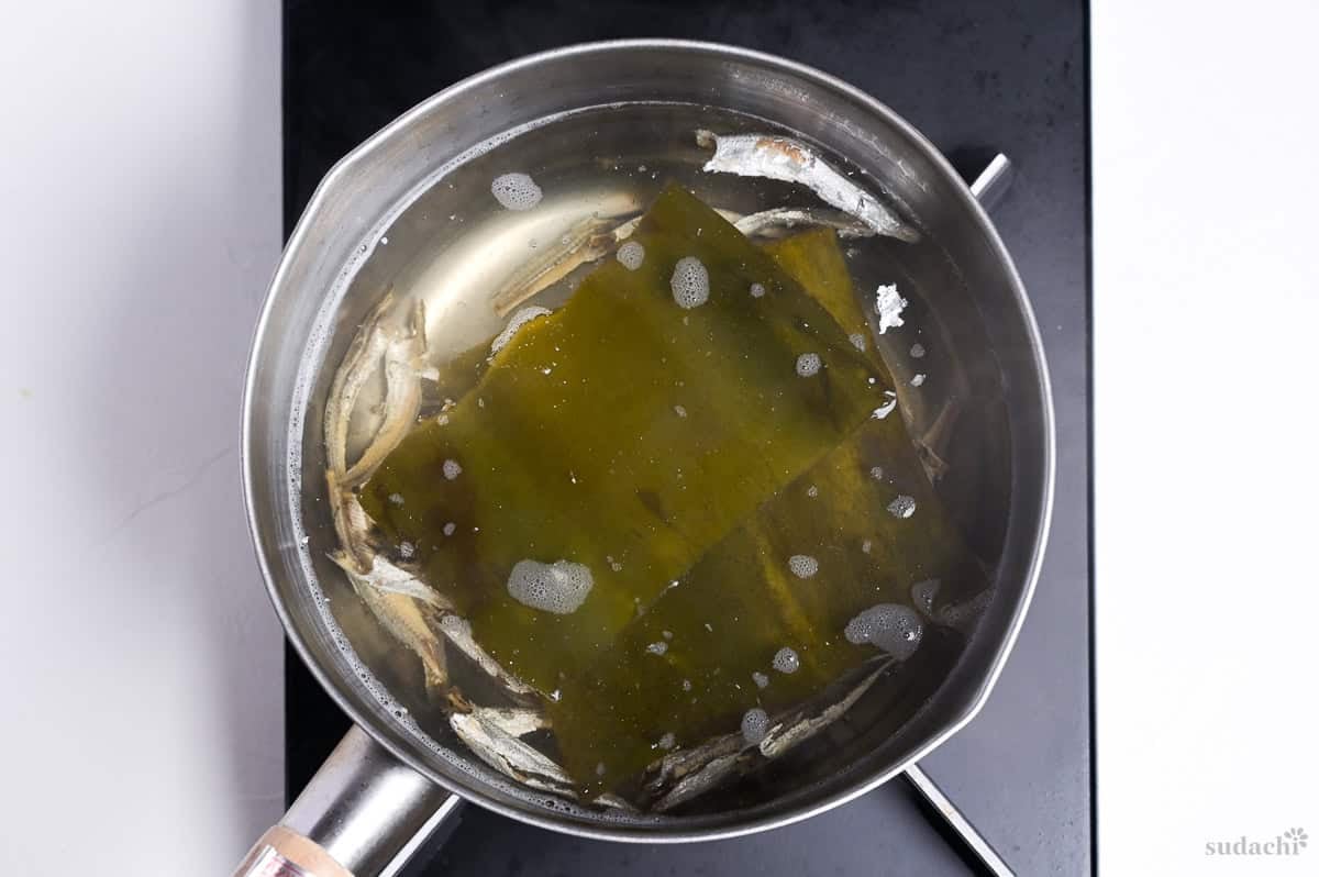 Simmering kelp and dried sardines in a pot of water on the stove top to make dashi