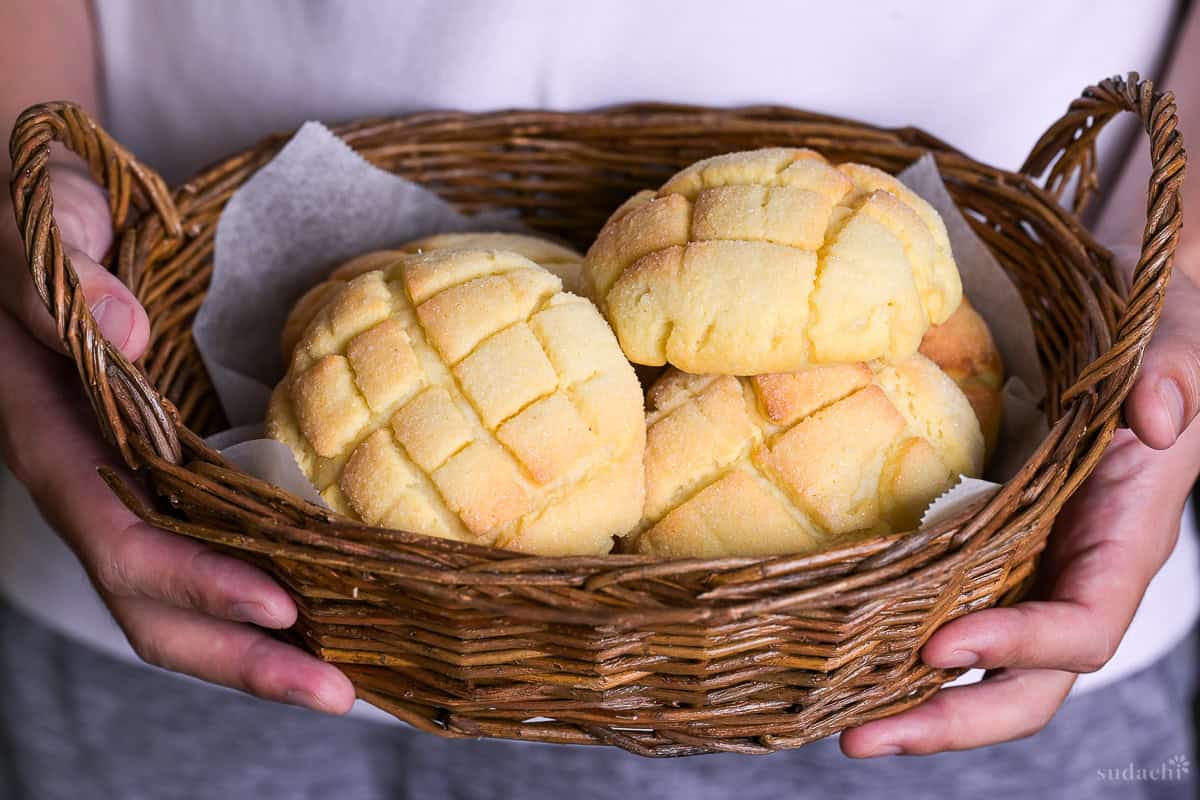 Yuto Omura holding six homemade Japanese melon pans in a wicker basket lined with white parchment paper