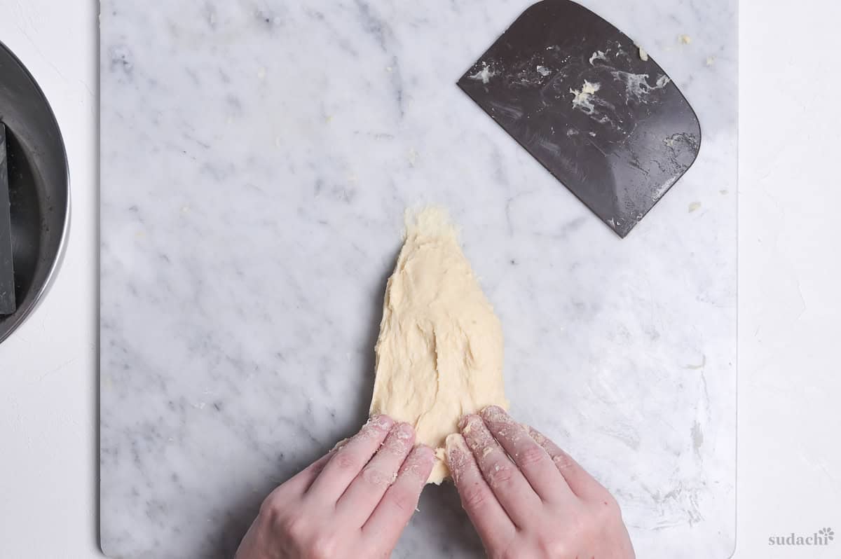 stretching bread dough on a marble kneading board