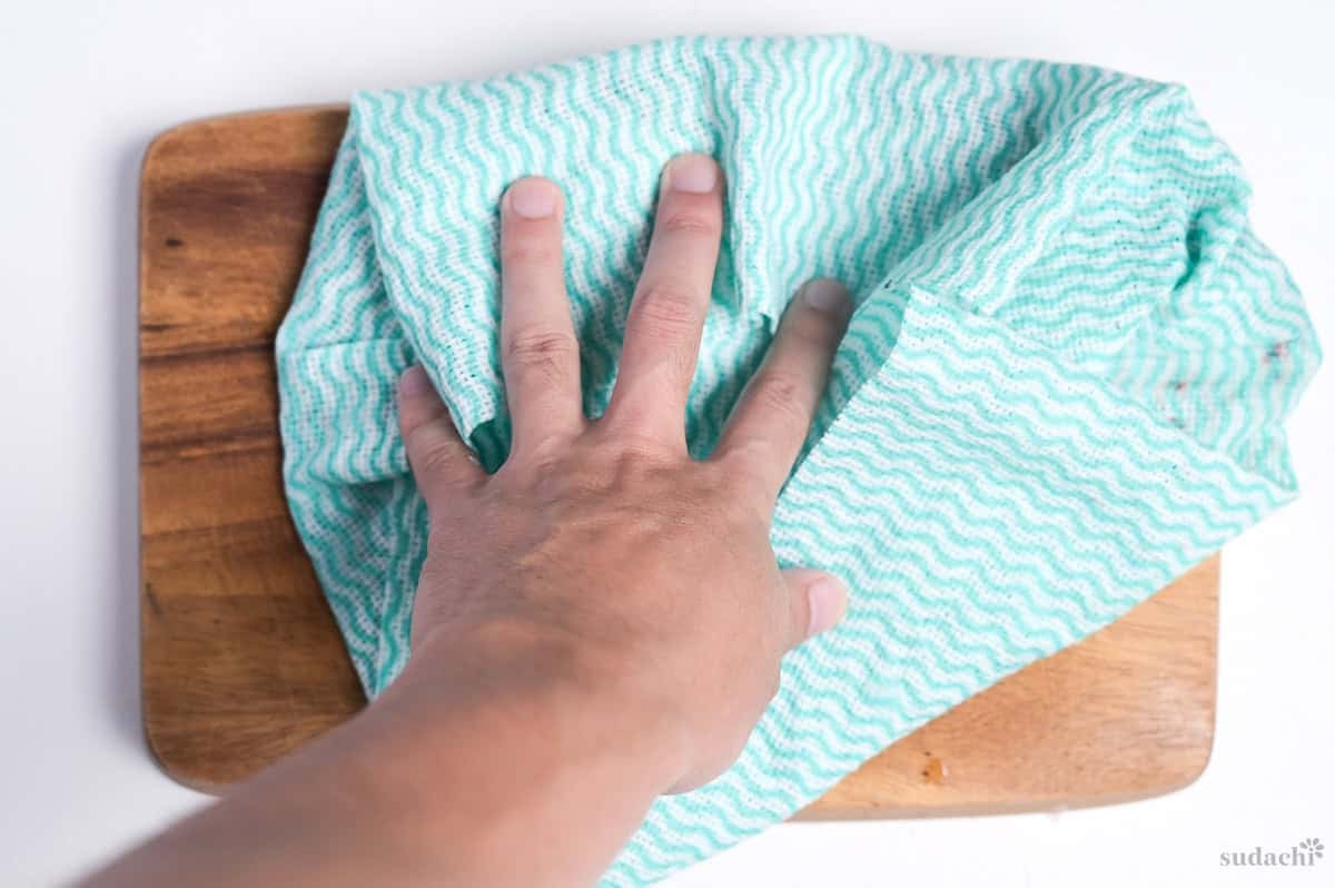 patting fish dry with a green kitchen cloth