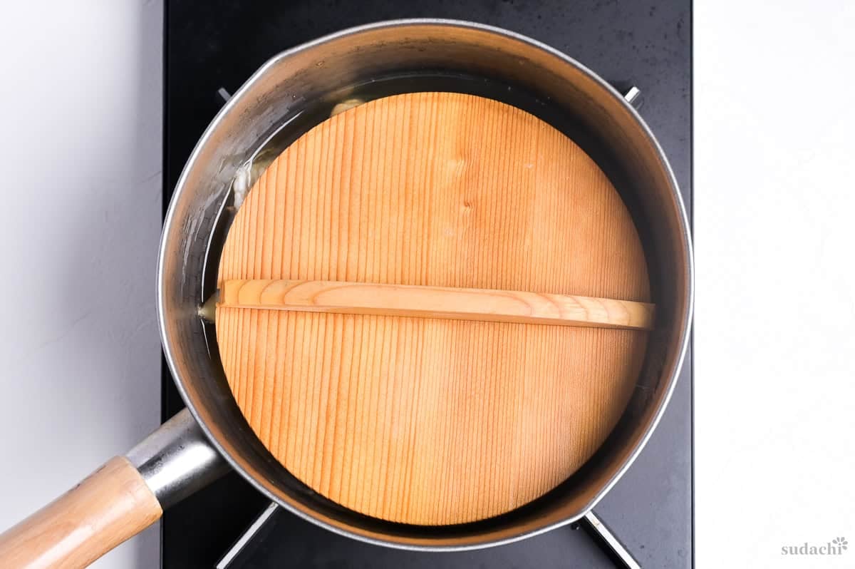 simmering fish in Japanese style broth with drop lid on top