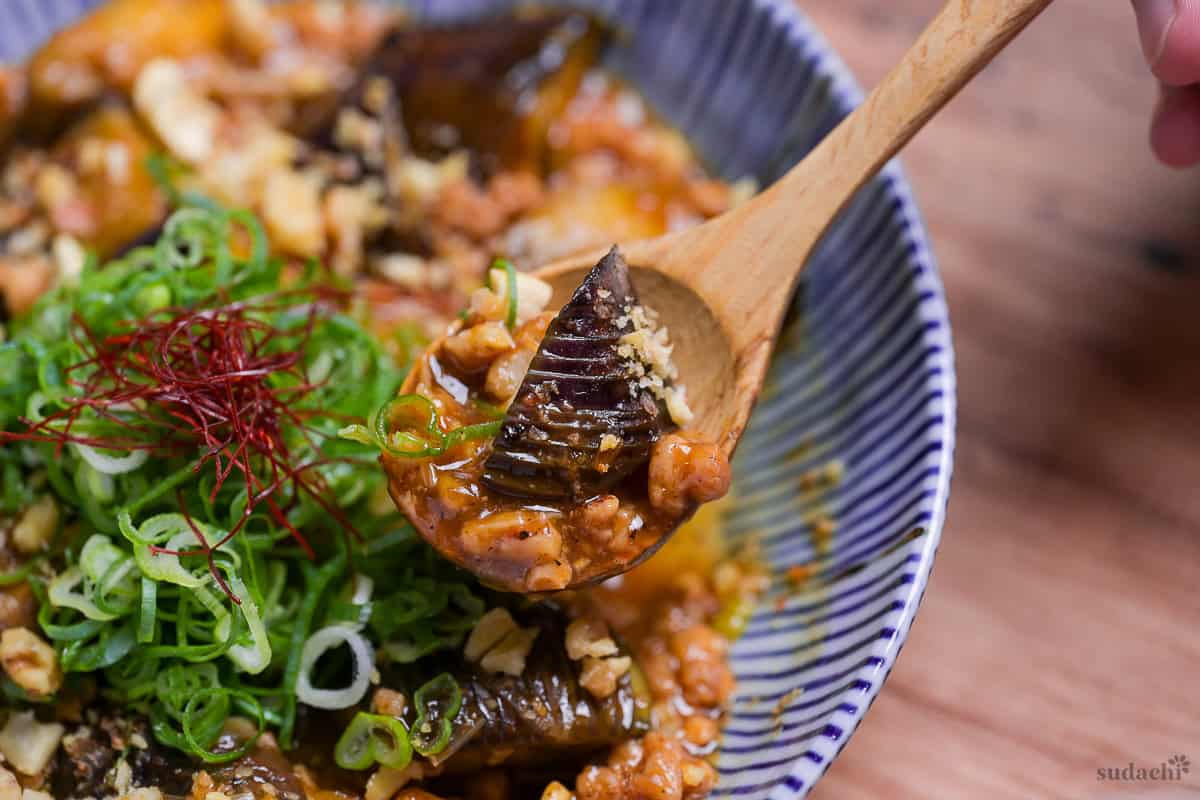 Plant-based mabo nasu (mapo eggplant) scooped onto a wooden spoon