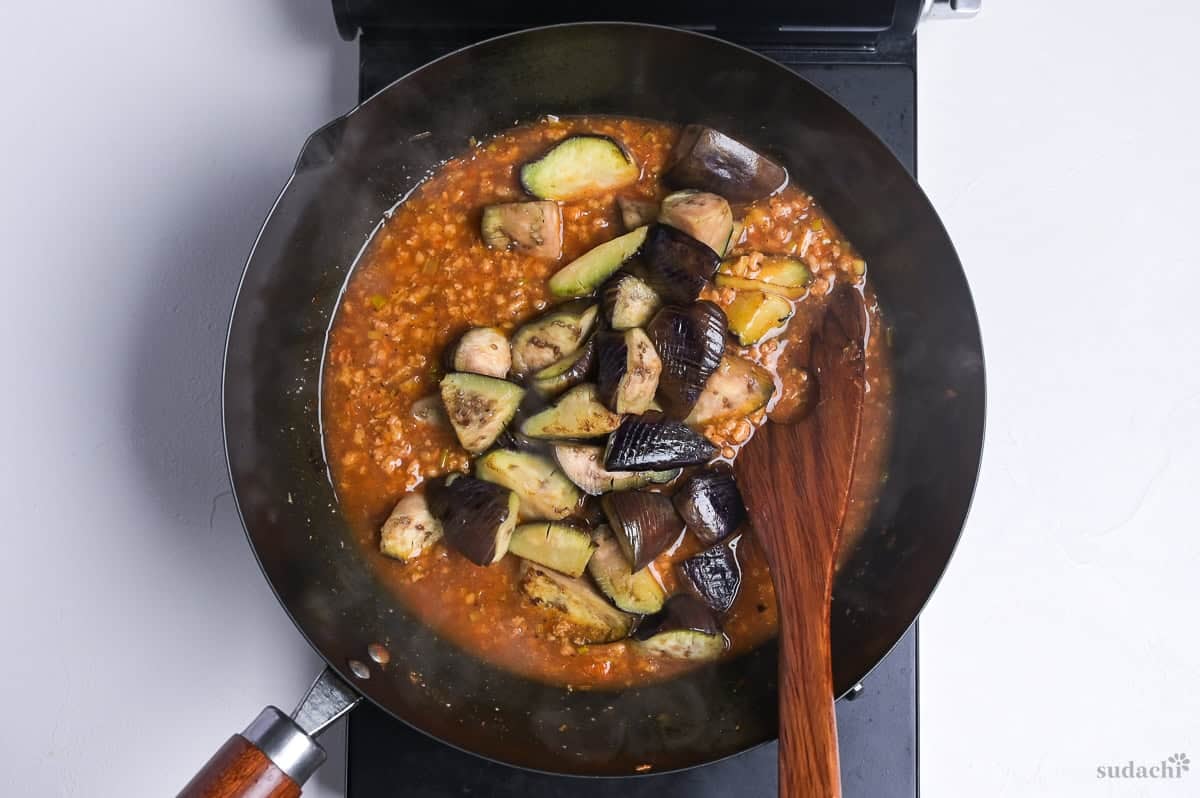 pan fried eggplant added back into plant-based mabo nasu sauce in wok on the stove top