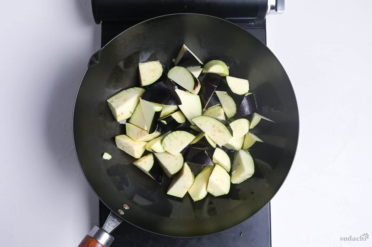 roughly cut Japanese eggplant in a large wok on the stove top