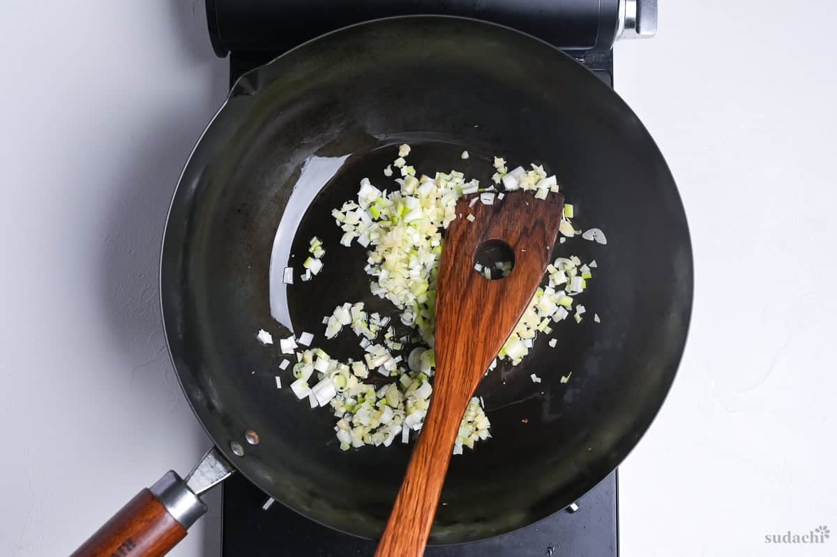 finely diced leek, garlic and ginger frying in a wok on the stove top