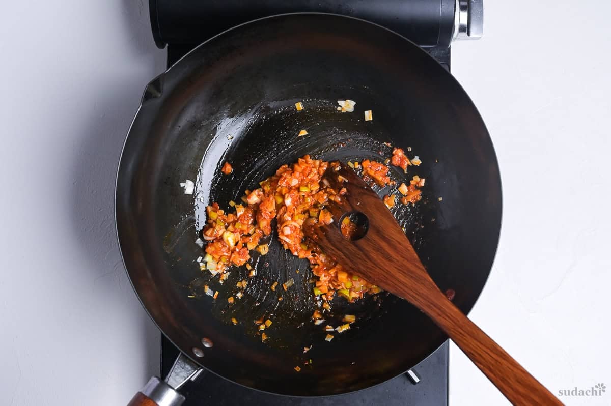 blooming doubanjiang in a hot wok on the stove top