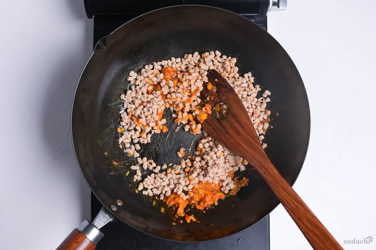 soy meat (mince style) mixed with aromatics and doubanjiang in a wok on the stove top