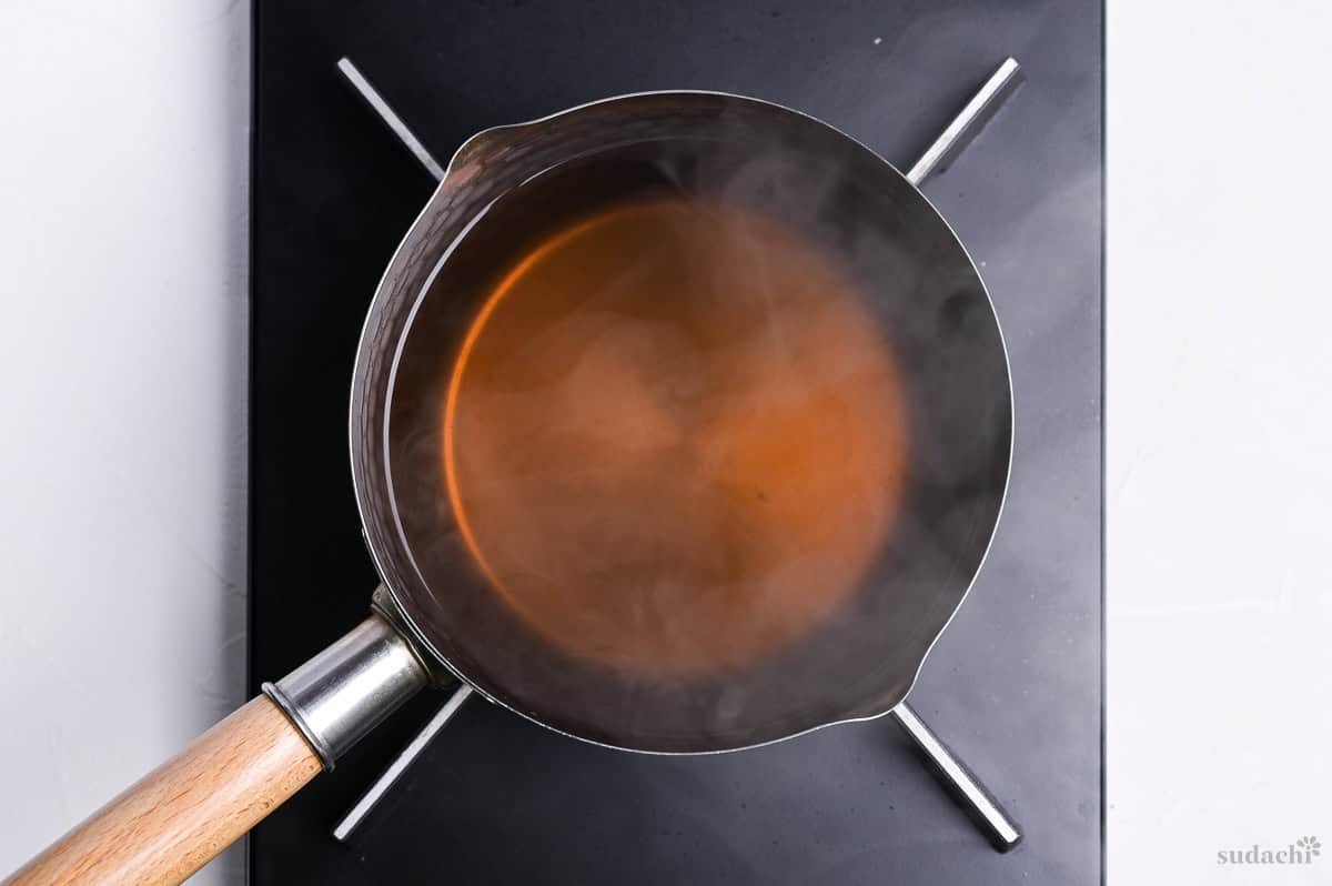 homemade udon noodle soup heated in a pot on the stove top
