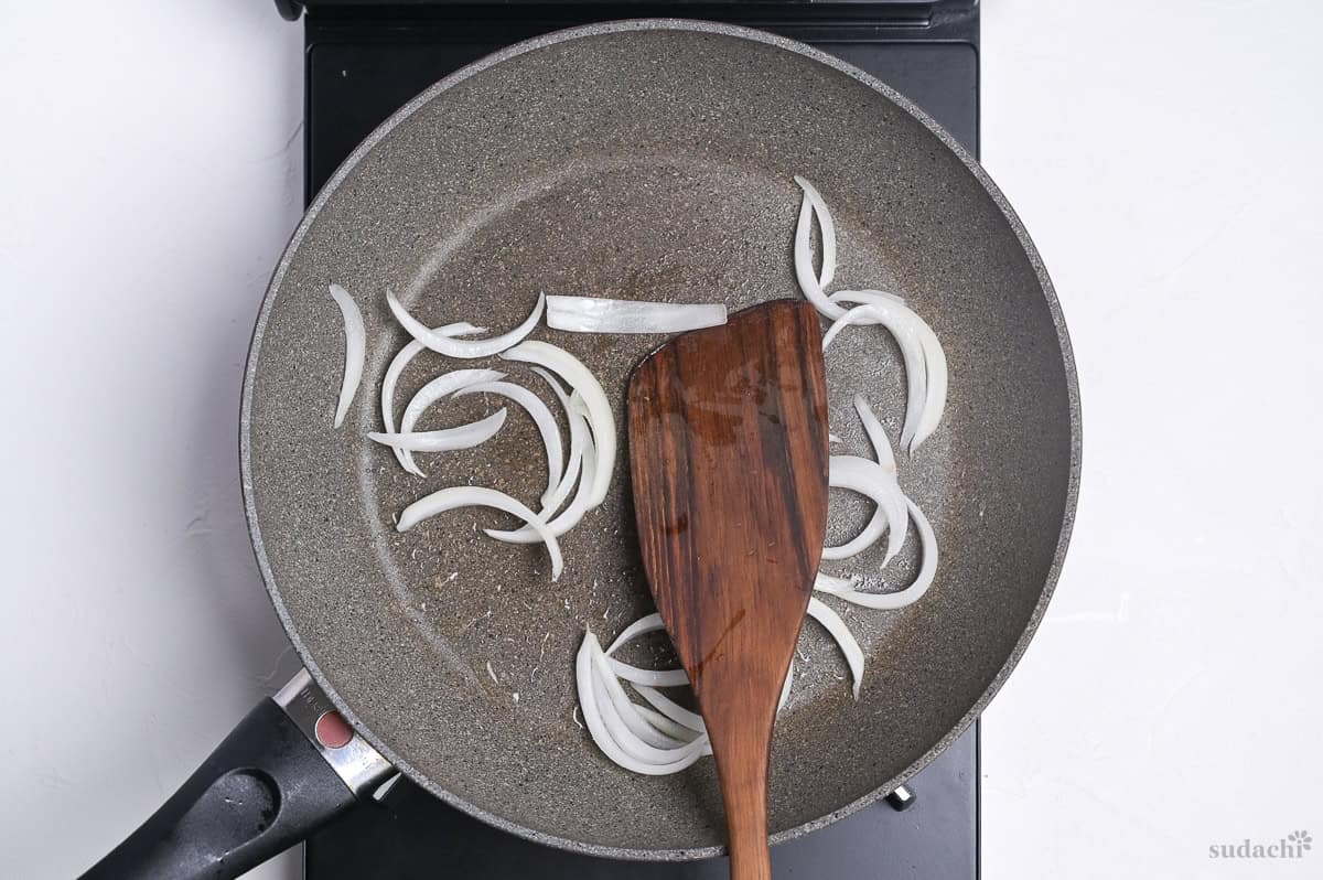 softening onions in a frying pan on the stove top